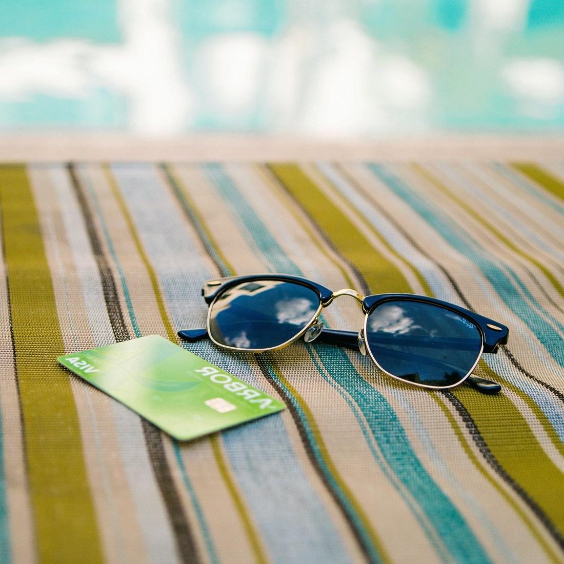太阳镜和阿伯牌借记卡放在沙滩浴巾上.